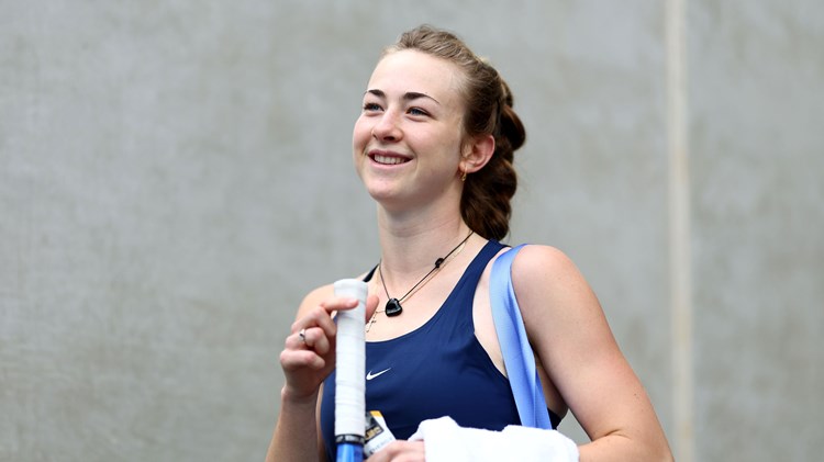 Mika Stojsavljevic holding her tennis racket in her hand and smiling on court at the Billie Jean King Cup Qualifiers in Australia