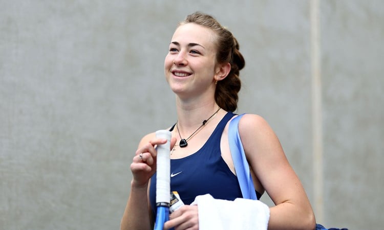 Mika Stojsavljevic holding her tennis racket in her hand and smiling on court at the Billie Jean King Cup Qualifiers in Australia