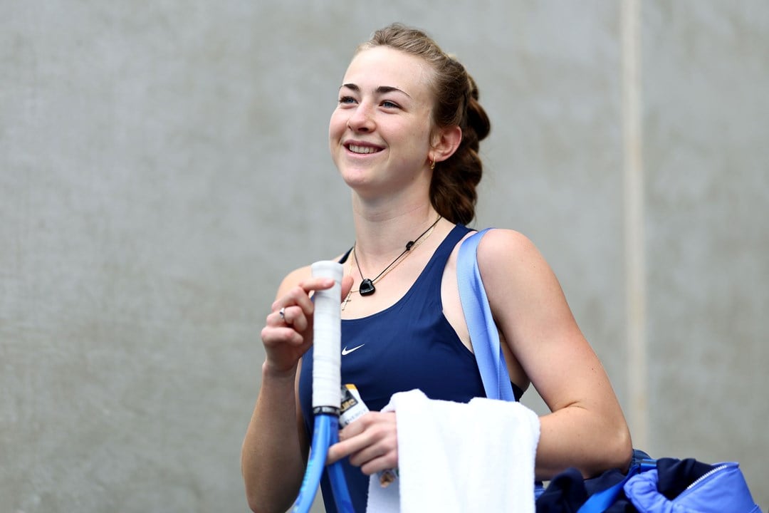 Mika Stojsavljevic holding her tennis racket in her hand and smiling on court at the Billie Jean King Cup Qualifiers in Australia