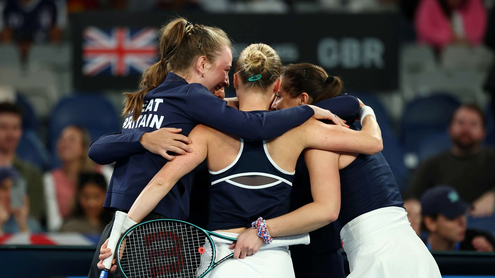 The Great Britain Billie Jean King Cup team hug in celebration after beating Australia