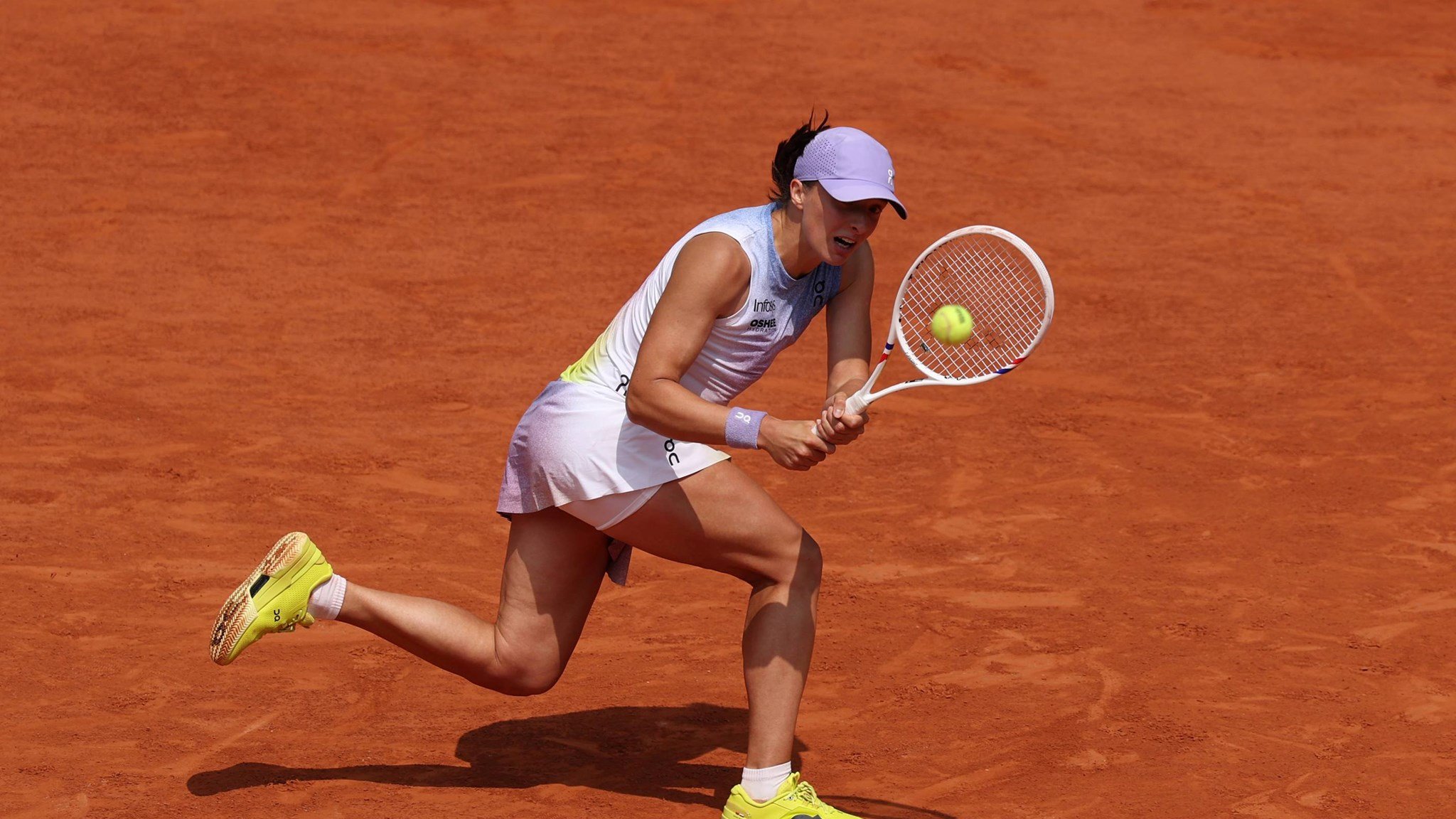 Iga Swiatek hits a backhand at the 2025 Roland Garros