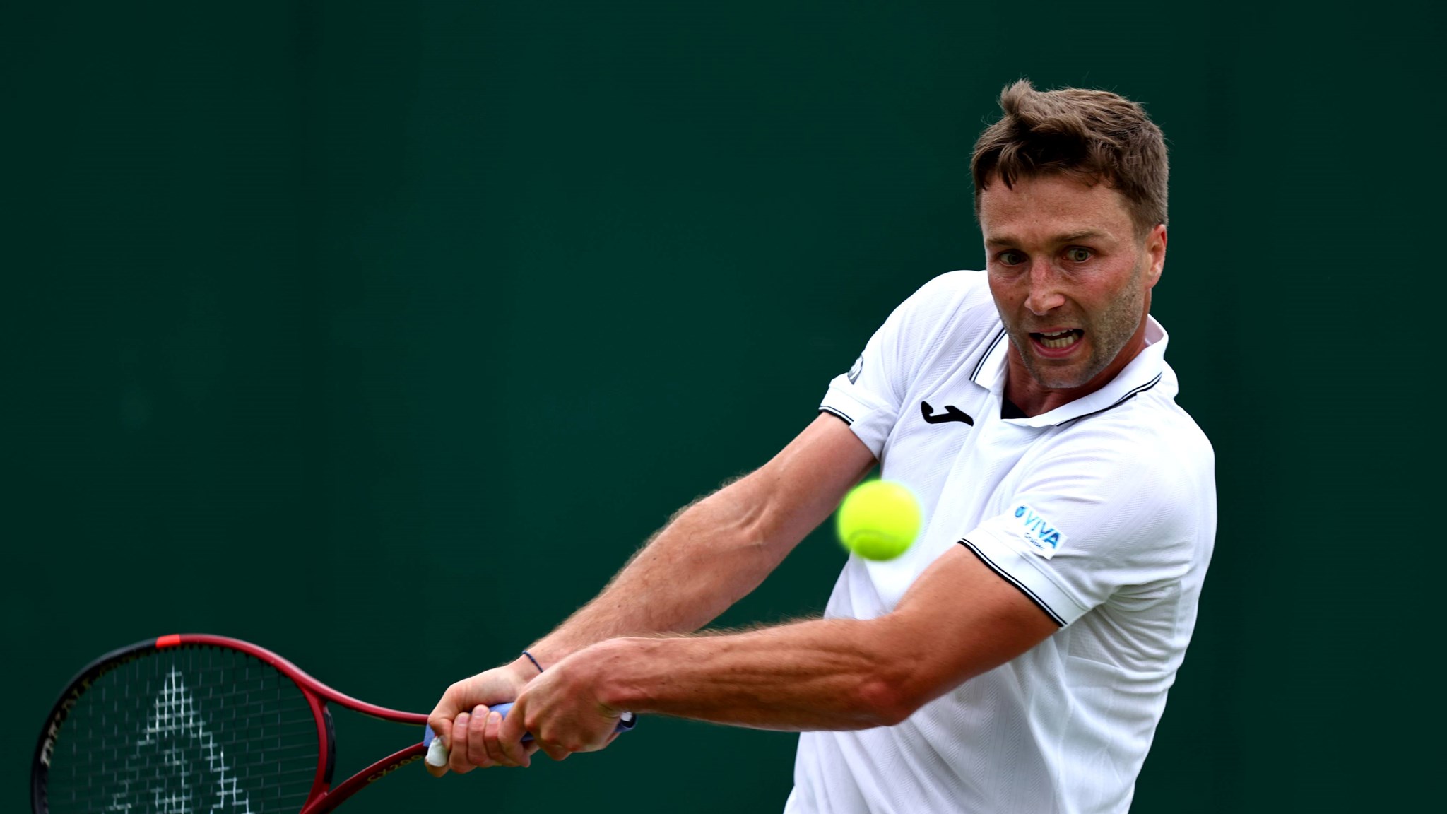 Liam Broady hitting a backhand at Wimbledon in 2024