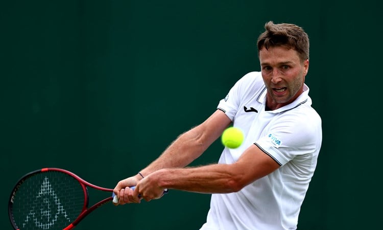 Liam Broady hitting a backhand at Wimbledon in 2024