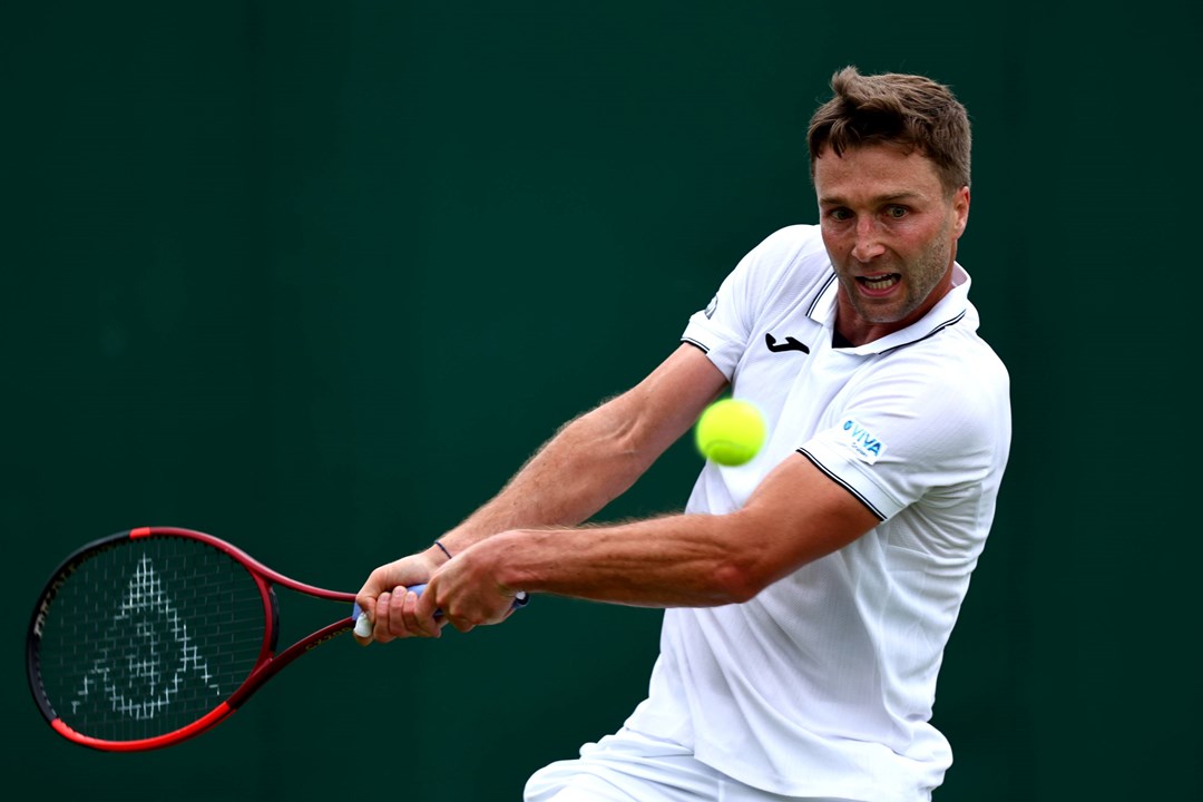 Liam Broady hitting a backhand at Wimbledon in 2024