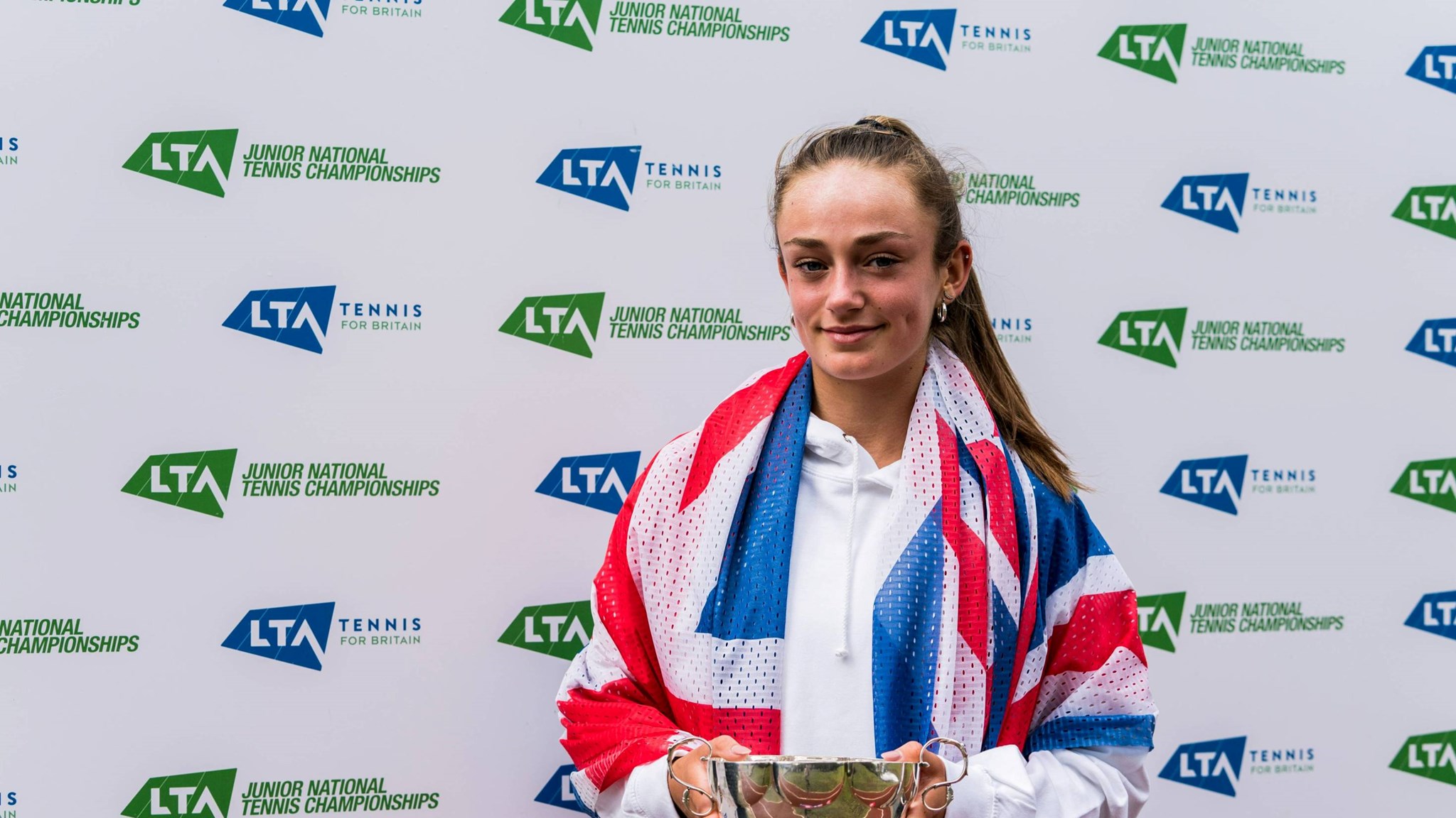 Isabelle Lacy hiding the 18U Junior National Championships trophy
