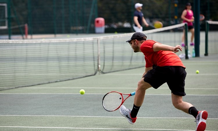 Club player reaching to hit a tennis ball on court