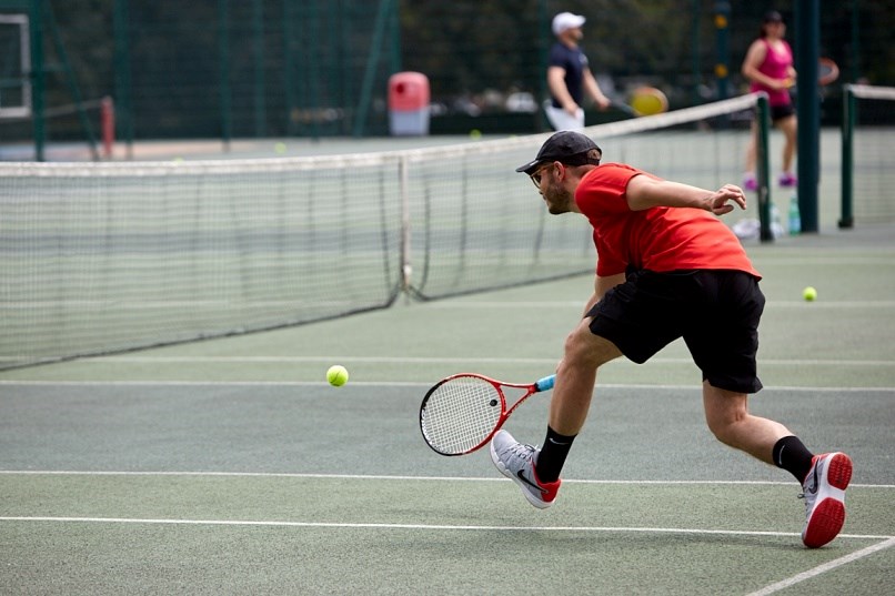 Club player reaching to hit a tennis ball on court