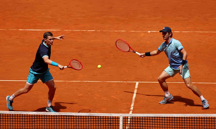 Neal Skupski hitting a backhand slice on court at the Madrid alongside Wesley Koolhof