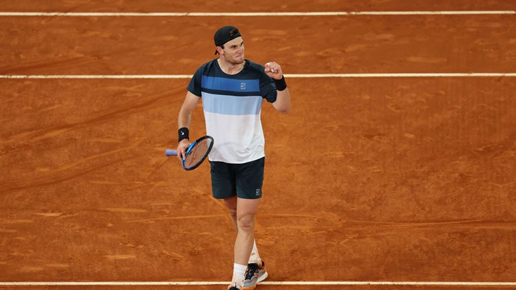 Jack Draper stood on a clay court at the Mutua Madrid Open while clenching his fist and holding his tennis racket