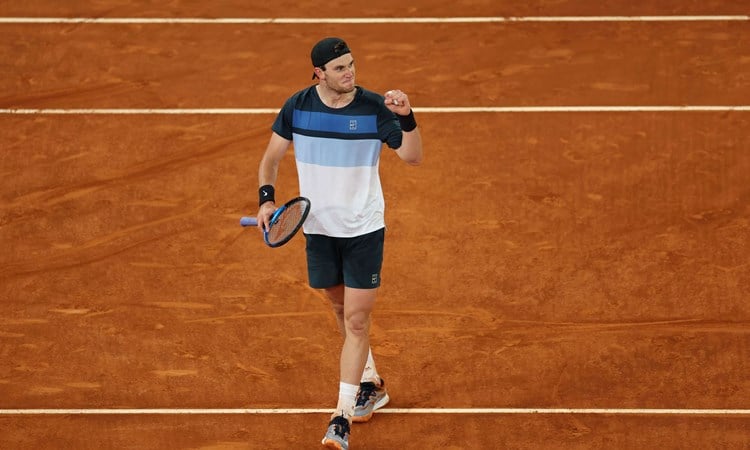 Jack Draper stood on a clay court at the Mutua Madrid Open while clenching his fist and holding his tennis racket