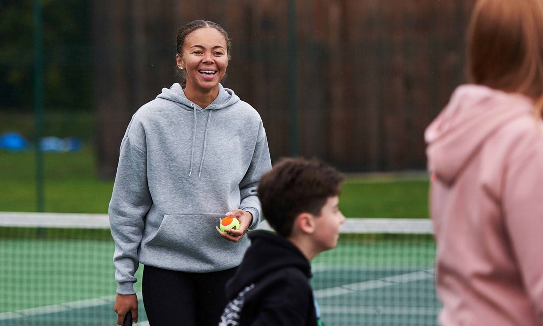 Tennis player on court laughing with friends
