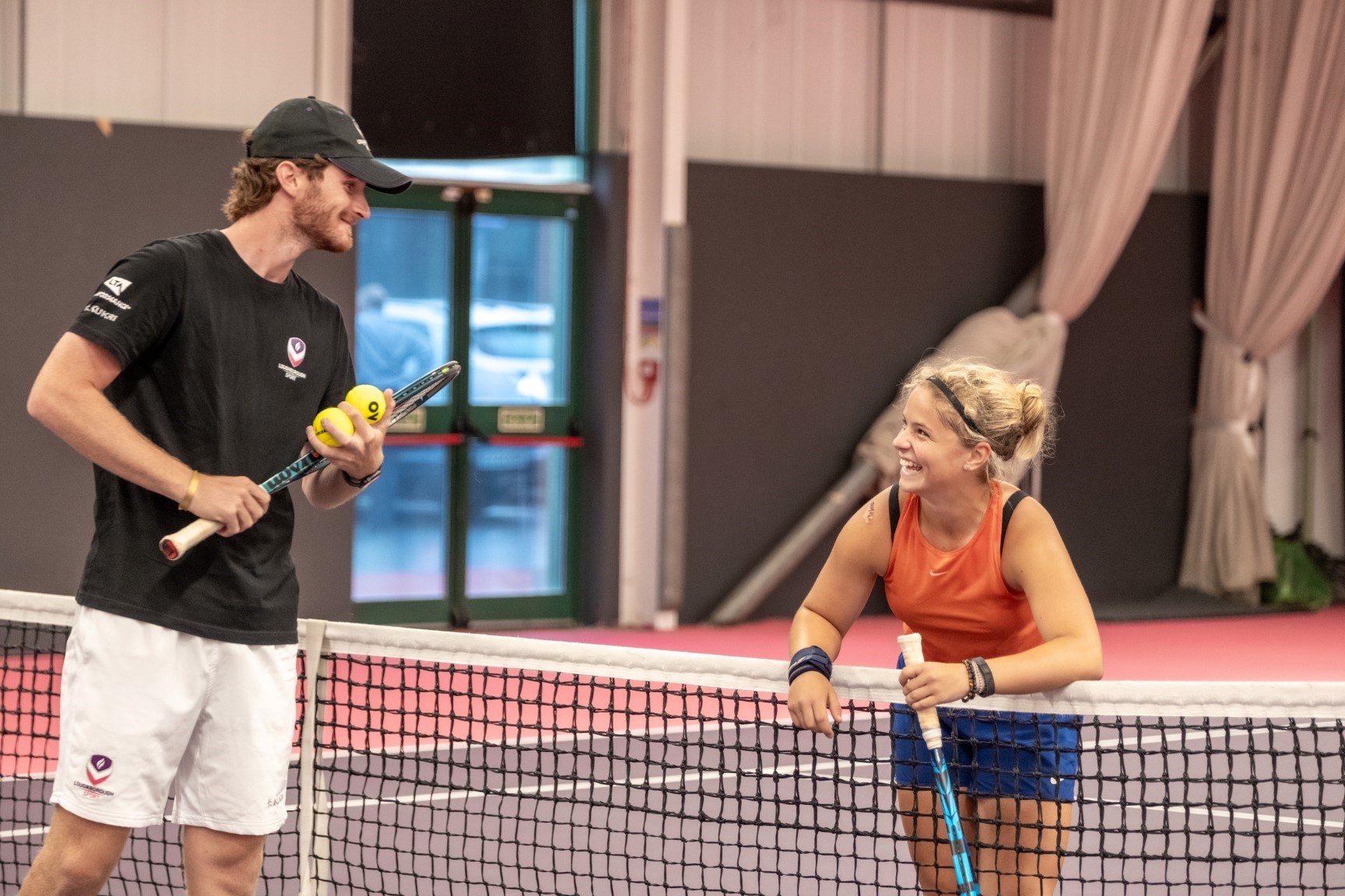 A player and coach on opposite sides of the net laughing