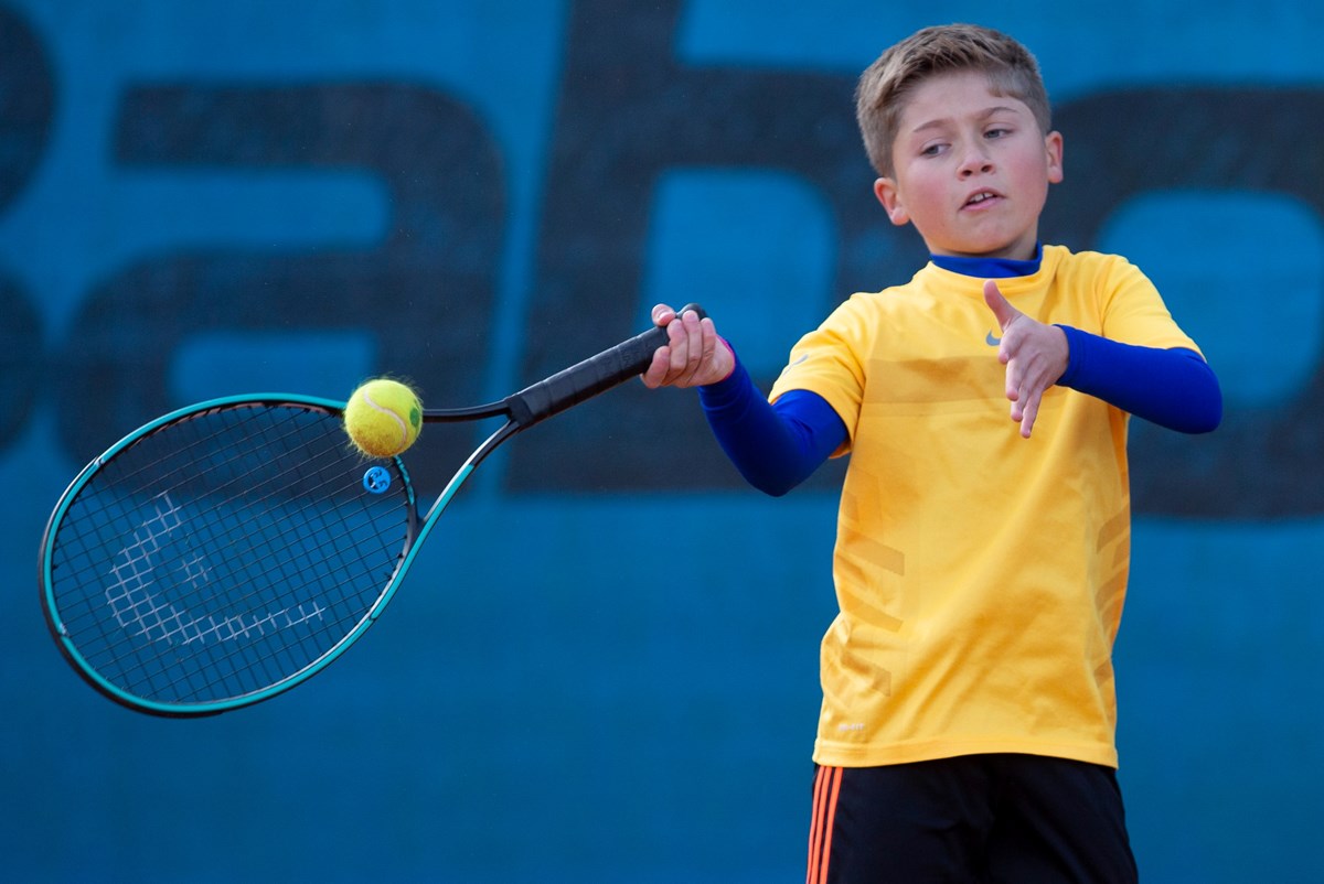 A young boy hitting a forehand in tennis