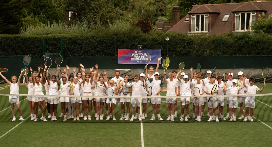 A group of players from the PLay Your Way to Wimbledon competition celebrating on court together