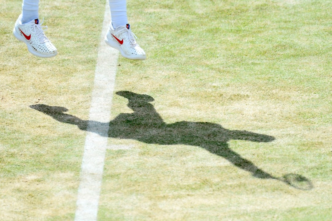 A shadow of a player serving on court