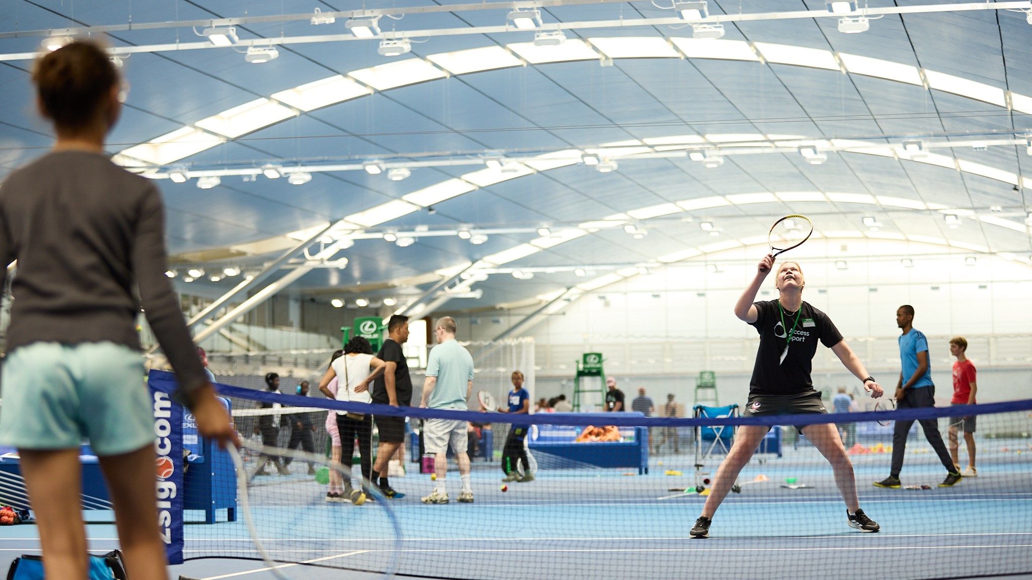 A volunteer vollleys a ball back to a participant