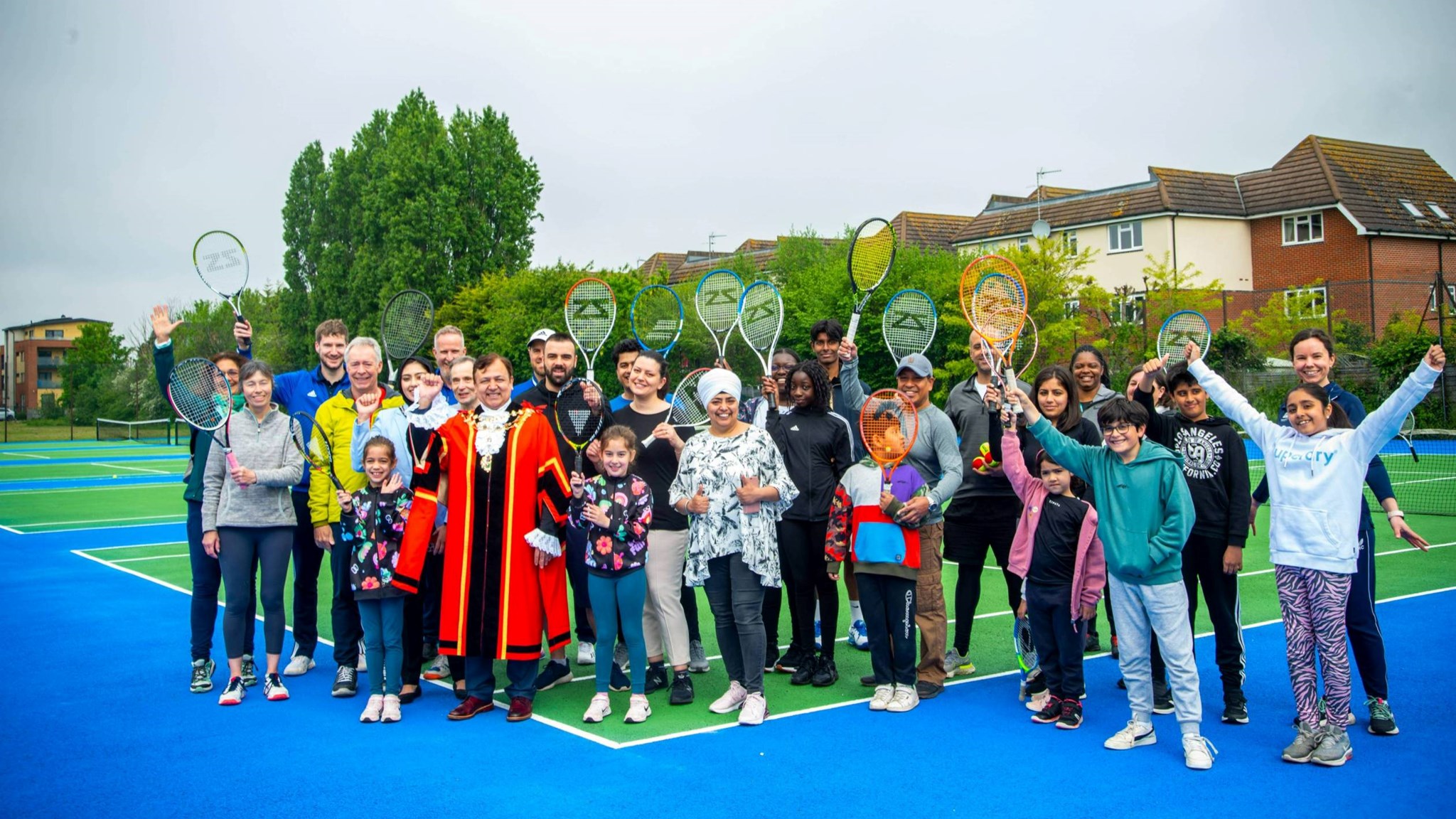 Members of the public raise their rackets for a photograph during the Rosendale Park re-opening in Hillingdon