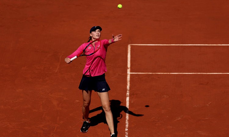 Elena Rybakina stood on a clay court while throwing a tennis ball in the air as she prepares to serve