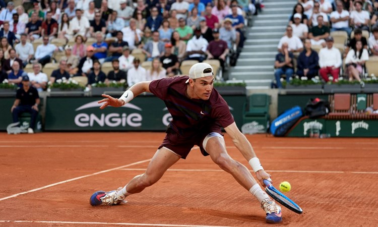 Jack Draper slides to hit a backhand against Alexander Bublik at Roland Garros