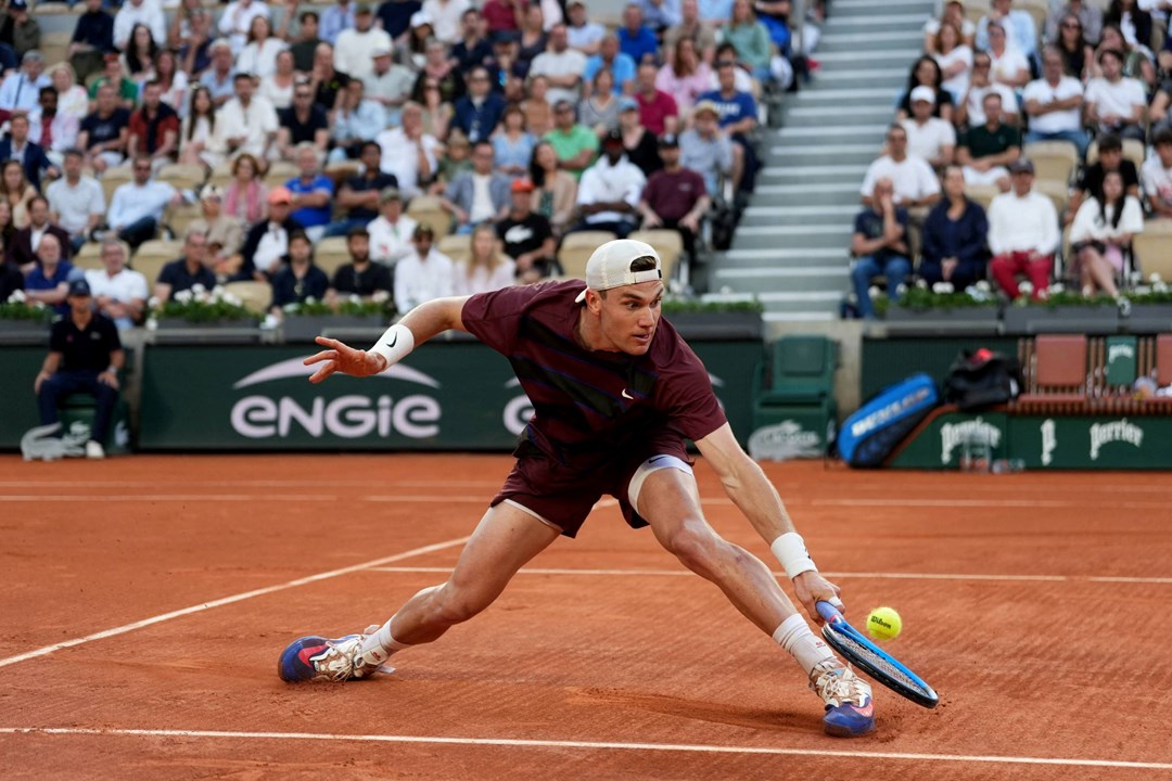 Jack Draper slides to hit a backhand against Alexander Bublik at Roland Garros