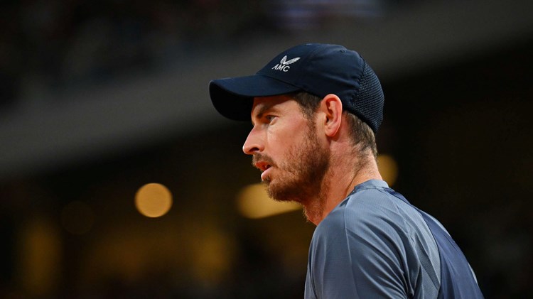 Andy Murray stood staring ahead on court while wearing a baseball cap