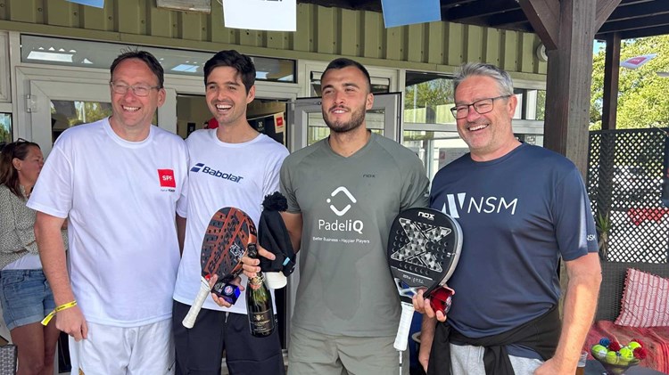 Louie Harris and Rafael Vega holding their padel bats, a bottle of champagne and their trophies alongside two men at the Padel British Tour event in Guernsey