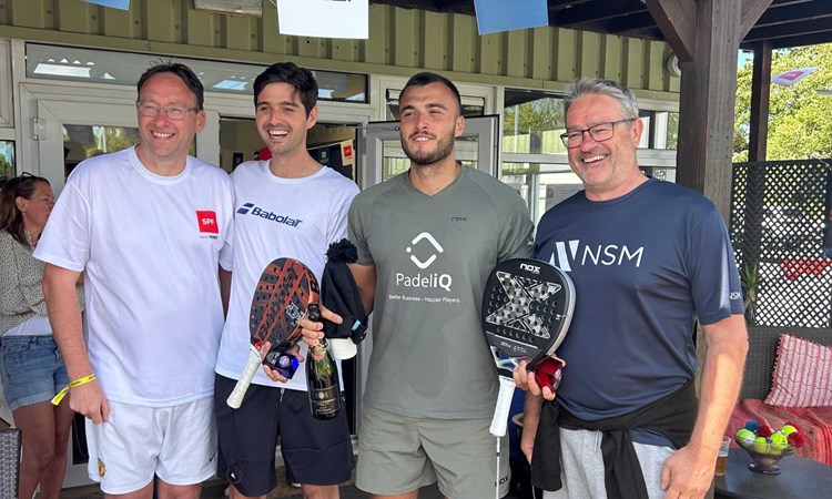 Louie Harris and Rafael Vega holding their padel bats, a bottle of champagne and their trophies alongside two men at the Padel British Tour event in Guernsey