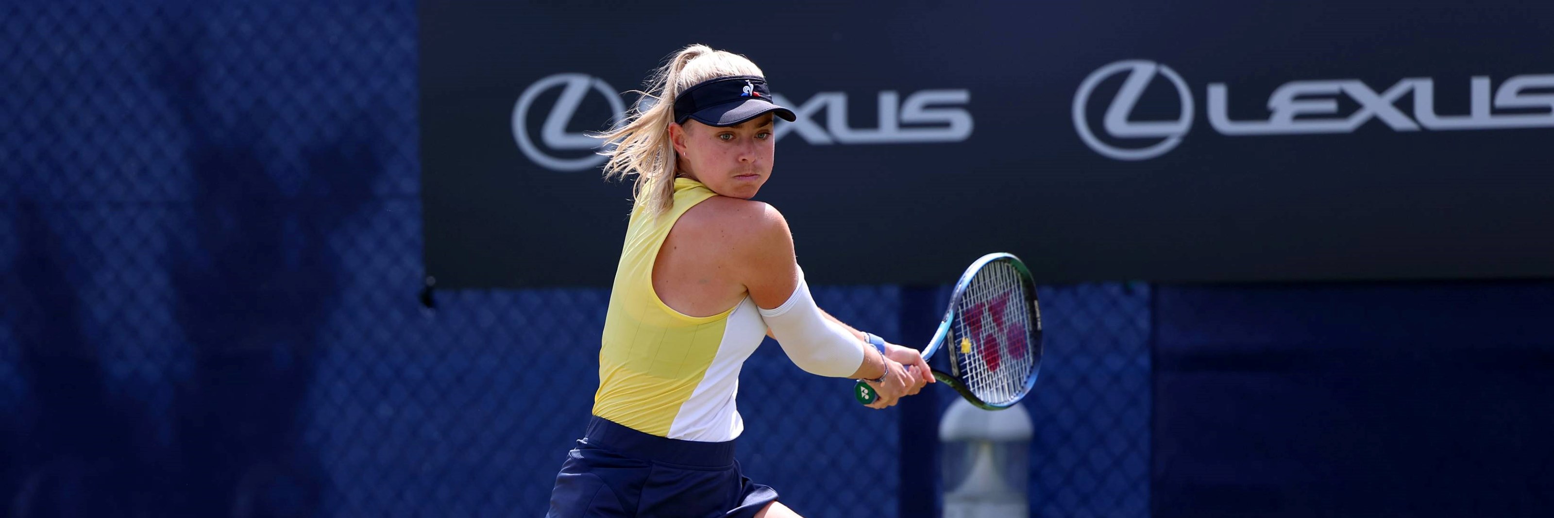 Emily Appleton stretching on court to hit a backhand at the Lexus Surbiton Open