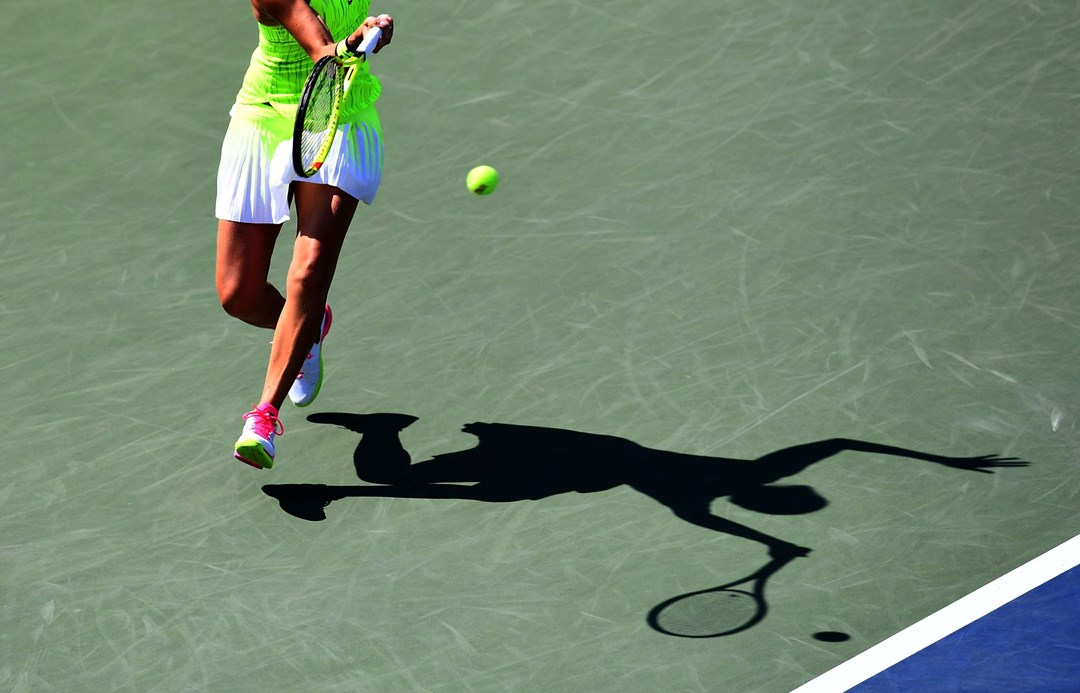 A female tennis player hitting a shot on a hard court