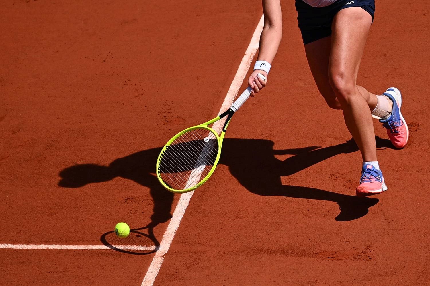 Female tennis player stretching for the ball on a clay court
