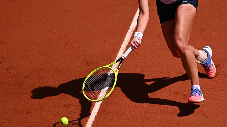 Female tennis player stretching for the ball on a clay court