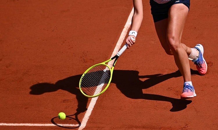 Female tennis player stretching for the ball on a clay court