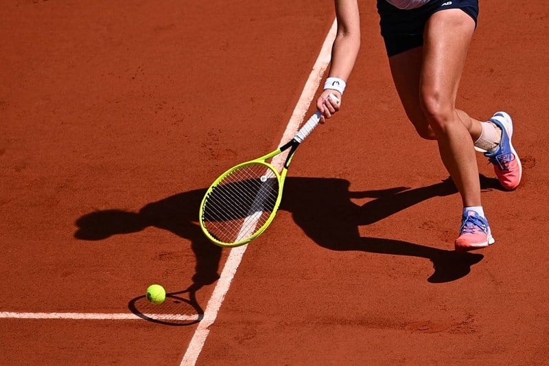 Female tennis player stretching for the ball on a clay court