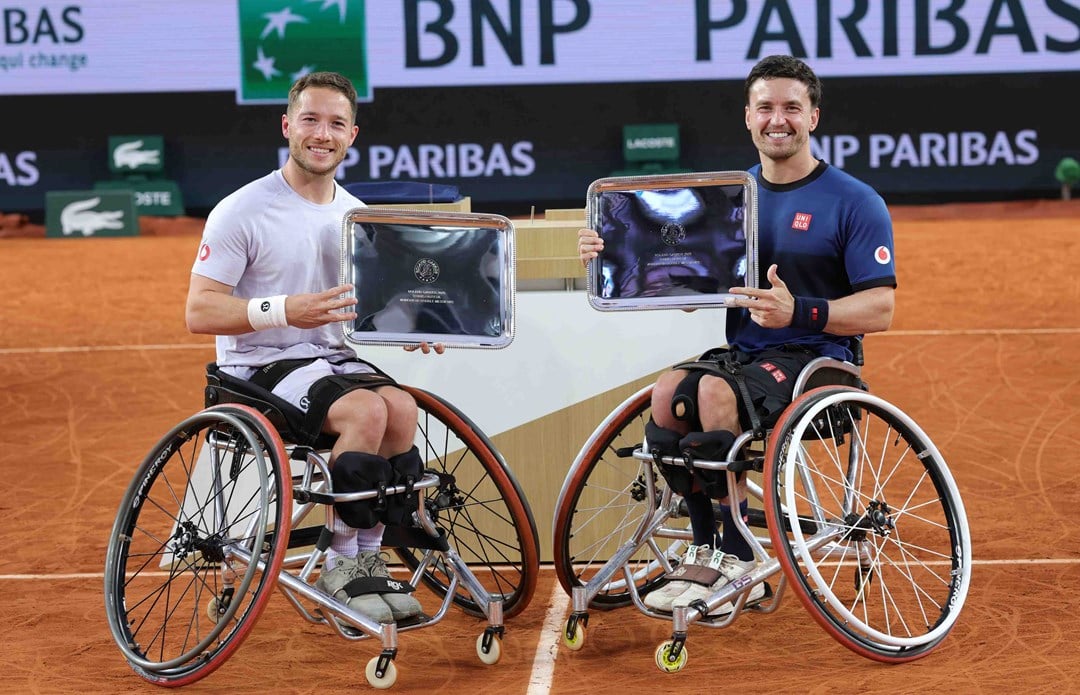 Alfie Hewett and Gordon Reid smiling while holding their winners trophies at Roland Garros