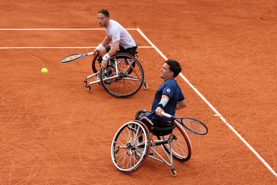 Gordon Reid about to hit a forehand on the clay with his partner Alfie Hewett looking on