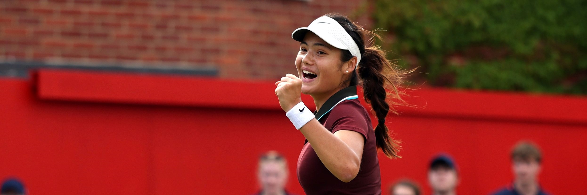 Emma Raducanu walking towards the back of the court while fist pumping and cheering in celebration