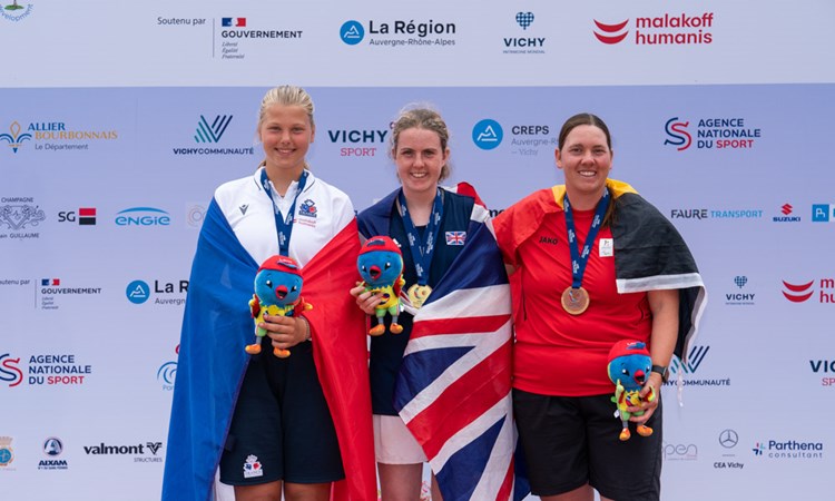 Gold medallist Anna McBride pictured on the winners' podium alongside her fellow competitors, holding the Virtus Global Games mascot.