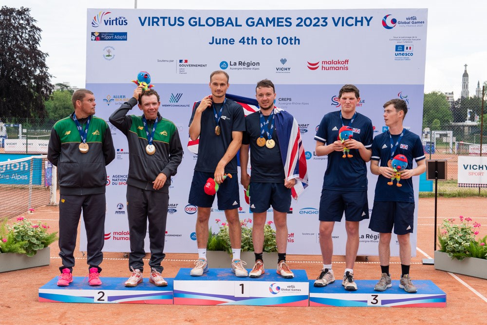 Dominic Iannotti and Fabric Higgins pictured on the winners podium alongside silver medallists Australia and bronze medallist, compatriots Oliver Beadle and Luke Turnball, after winning gold in the Men’s Doubles II1 at the 2023 Virtus Global Games. 