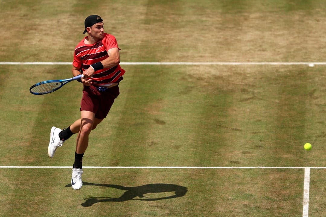 Jack Draper raises off the ground as he hits a forehand on the grass at the HSBC Championships