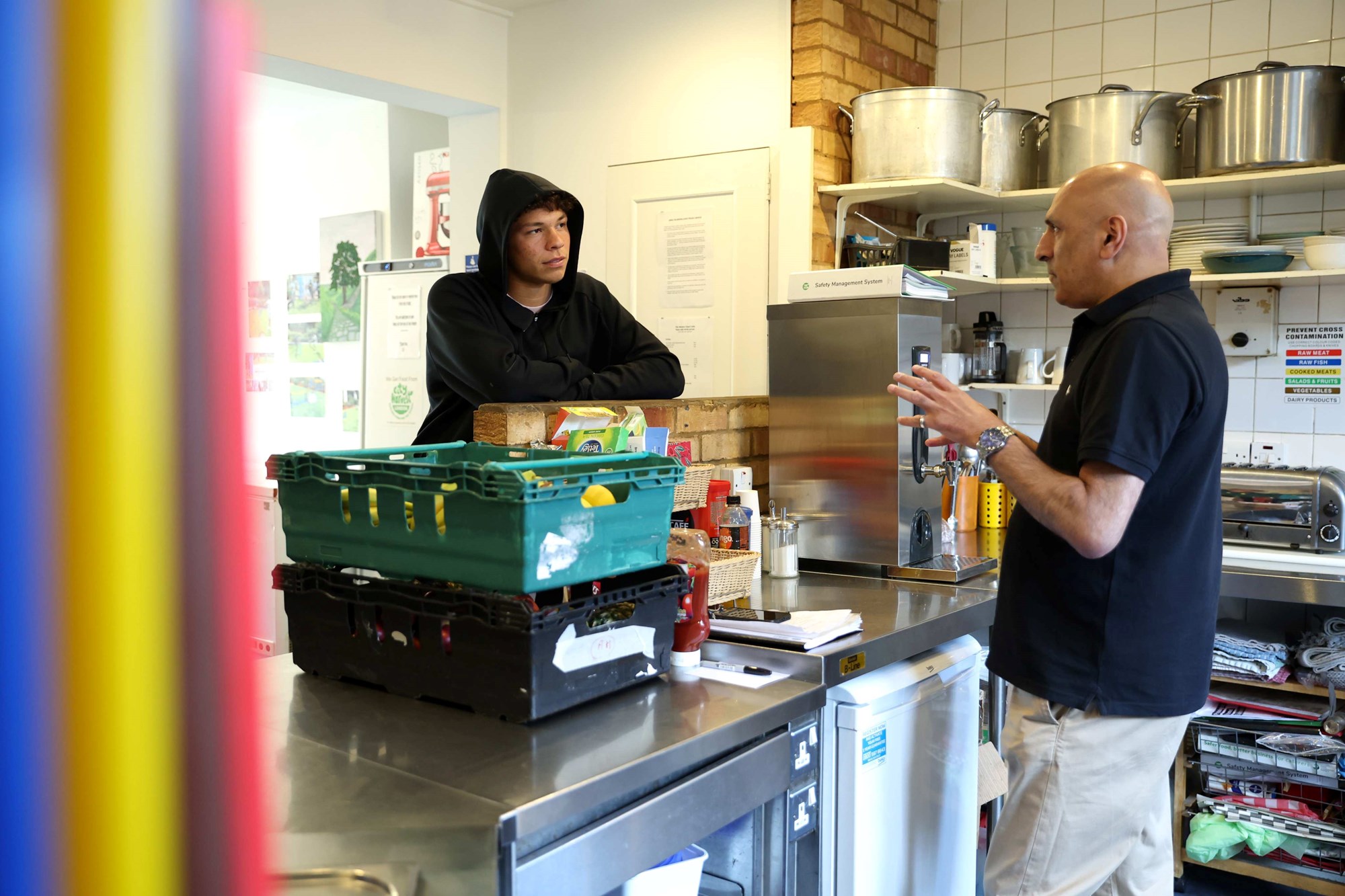 Ben Shelton leaning on a box while talking to a man in a kitchen at the food bank