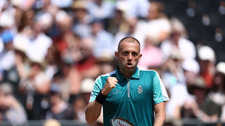 Dan Evans fist pumping in celebration while holding his racket in his other hand
