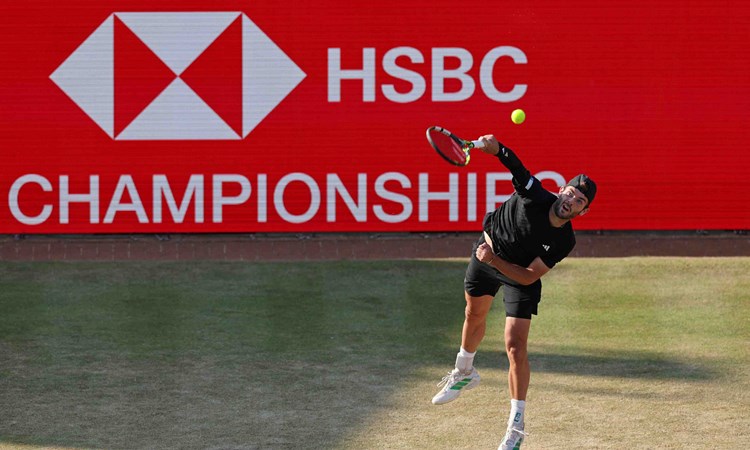 Jacob Fearnley reaching for a serve on the grass court at the HSBC Championships