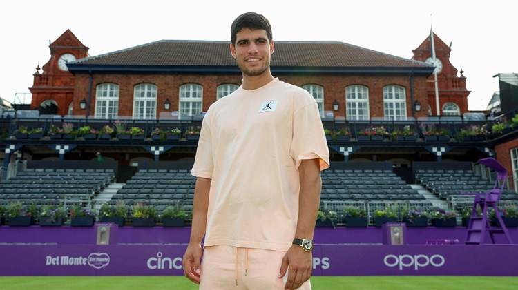 Carlos Alcaraz stood on court infront of the Queen's Club at the cinch Championships