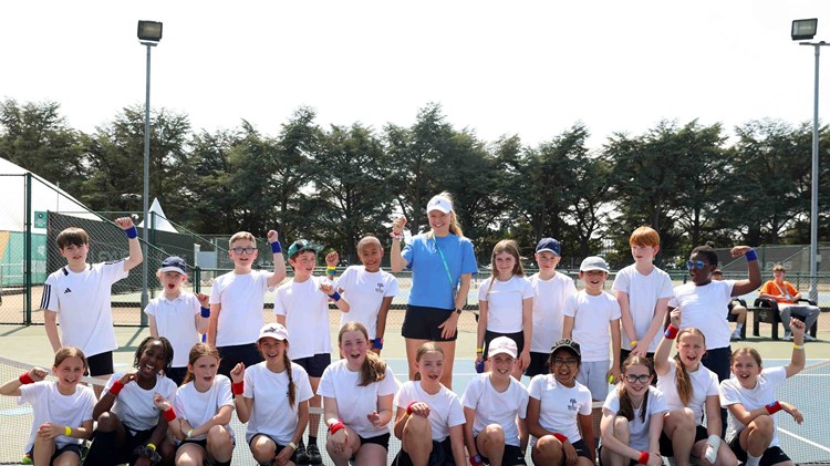 British tennis player Harriet Dart smiling and waving with a group of school kids on court in Nottingham