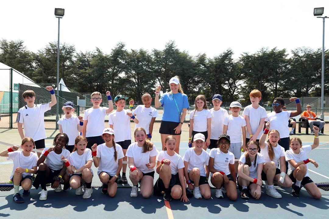 British tennis player Harriet Dart smiling and waving with a group of school kids on court in Nottingham