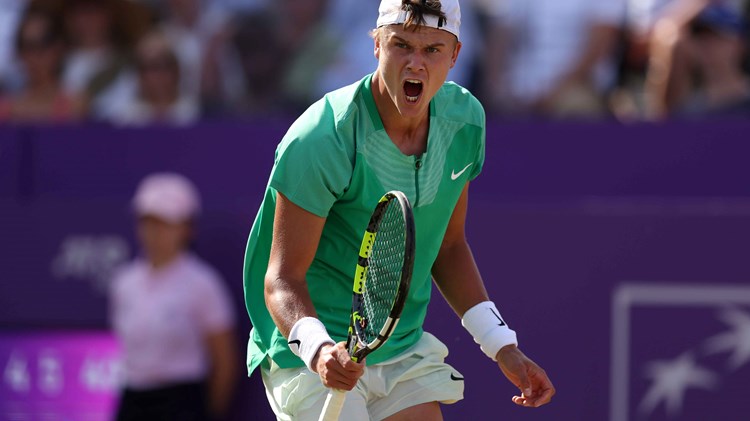 Holger Rune roaring in celebration while holding a tennis racket after winning his quarter-final match at the cinch Championships