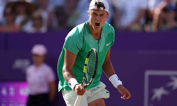 Holger Rune roaring in celebration while holding a tennis racket after winning his quarter-final match at the cinch Championships