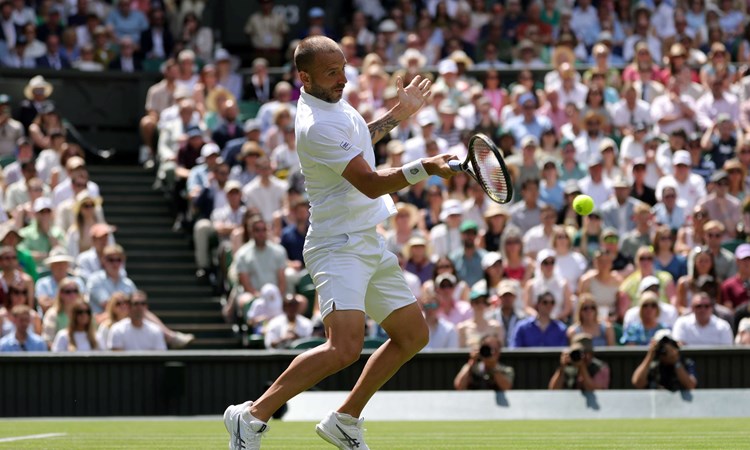 British tennis player Dan Evans hitting a forehand on Centre Court at Wimbledon during his second round match against Novak Djokovic 