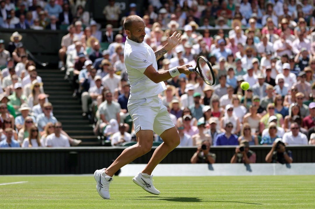British tennis player Dan Evans hitting a forehand on Centre Court at Wimbledon during his second round match against Novak Djokovic
