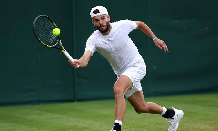 Jacob Fearnley reaching to hit a forehand on court at Wimbledon